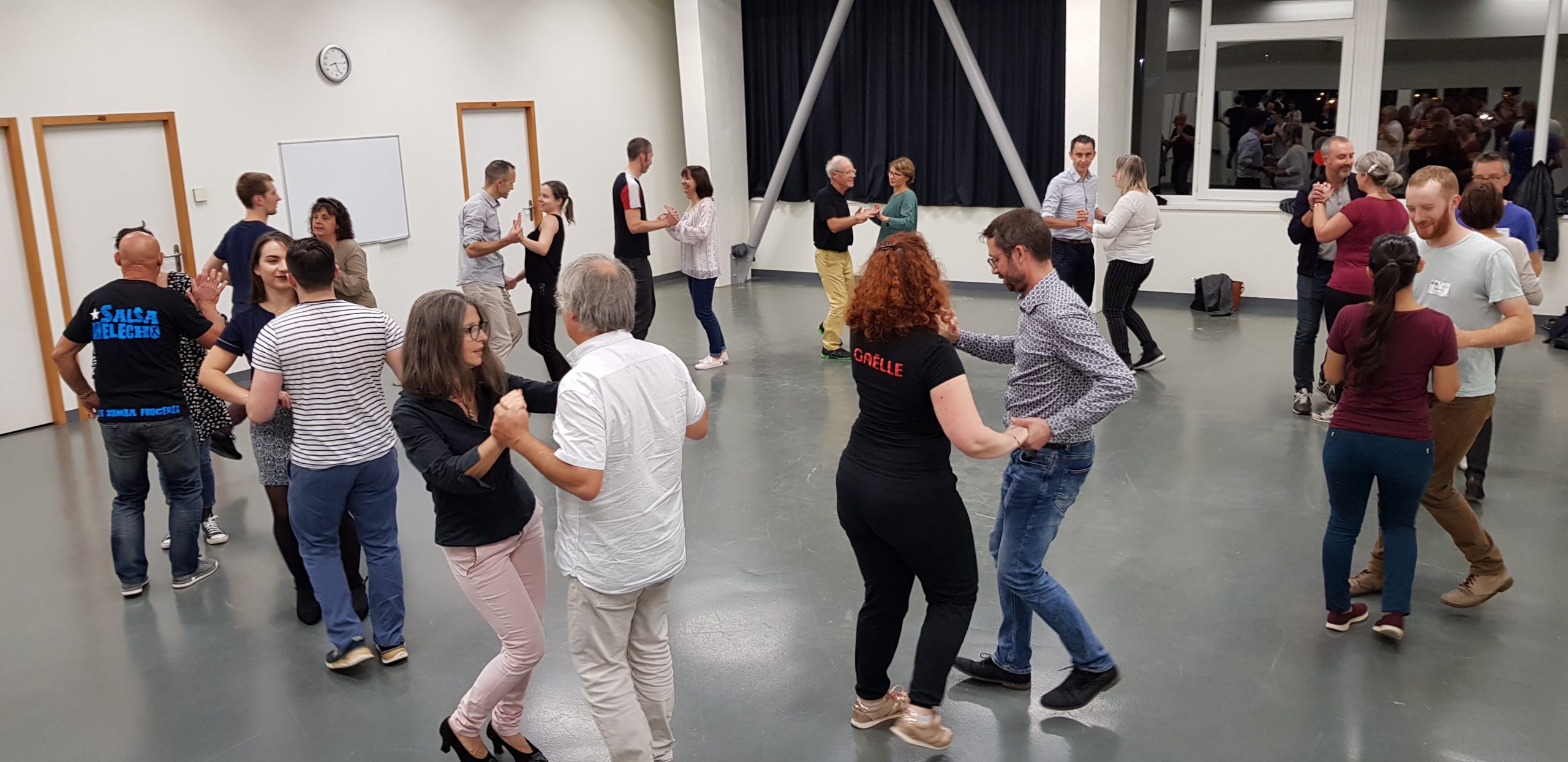 Un groupe de personnes participant à un cours de danse, se déplaçant en rythme sous la direction d'un instructeur.