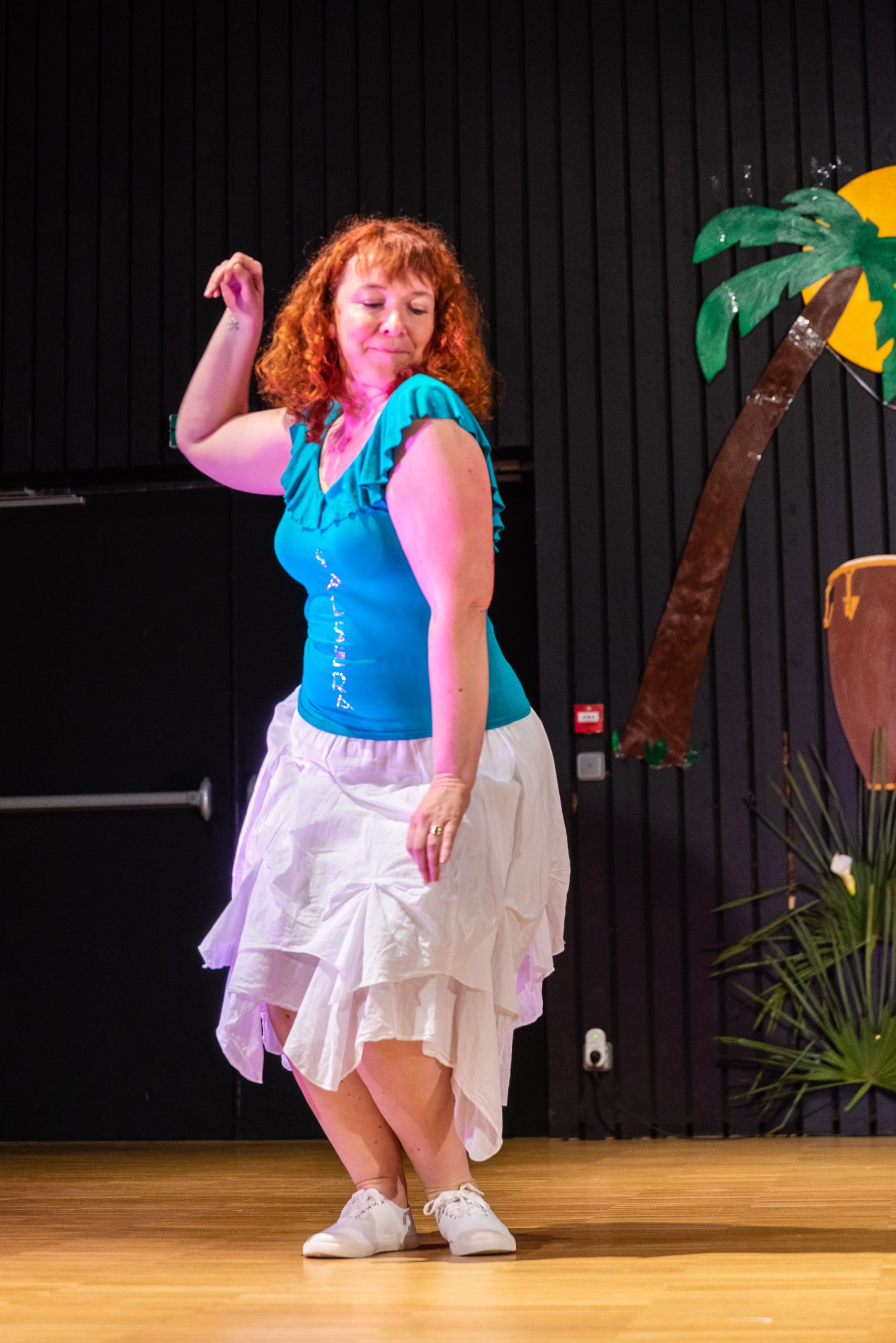Une femme vêtue d'une chemise et d'une jupe bleues effectue une danse.