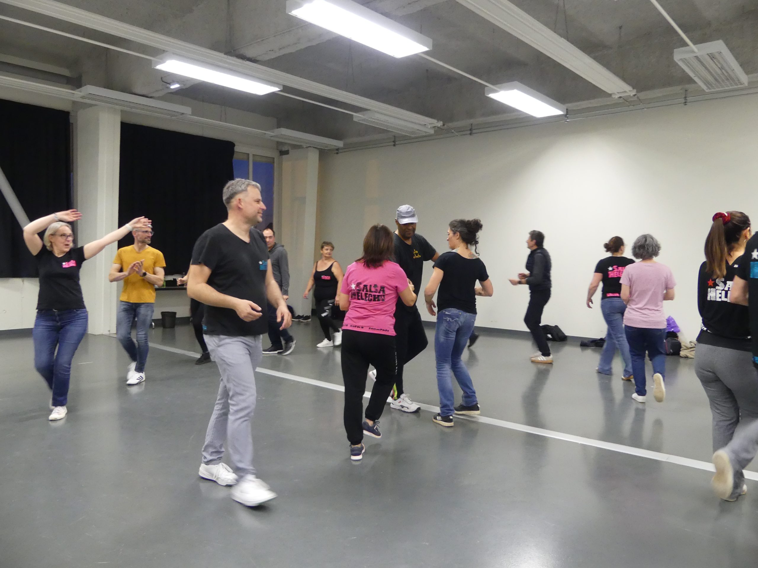 Des élèves dans un cours de danse, se déplaçant en rythme sous la supervision d'un instructeur.